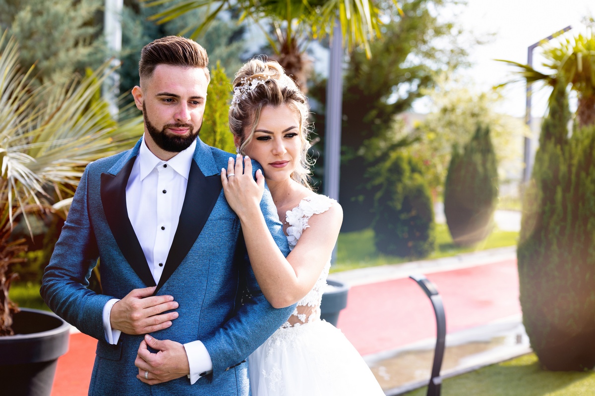 Cuplu fotografiat într-o grădină modernă în ziua nunții, cu lumini naturale și detalii elegante